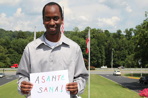 Photo of international student holding a sign saying "thank you" in Swahili.