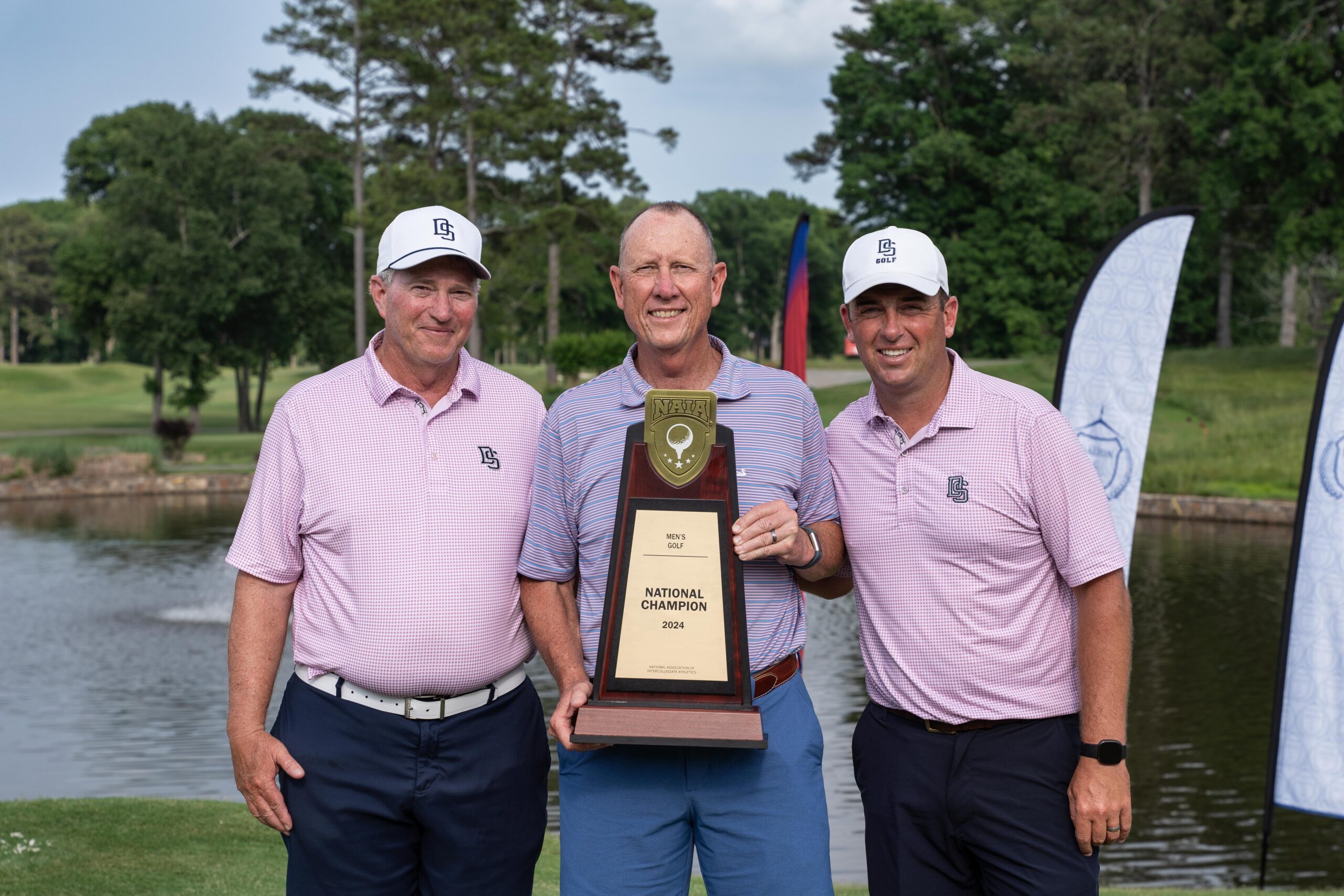 Jon Jaudon, center, poses with the men's 2024 NAIA Championship Golf trophy with golf coaches Ben Rickett (right) and Jim McGrew.