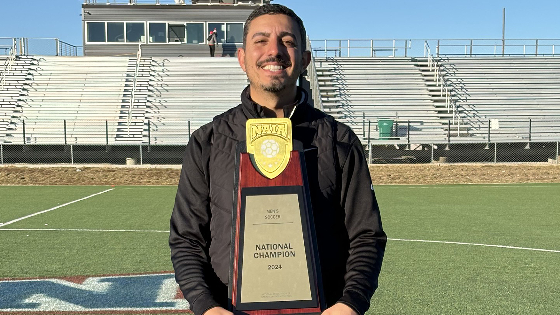 Saif Alsafeer poses with the 2024-2025 NAIA men's soccer championship trophy.